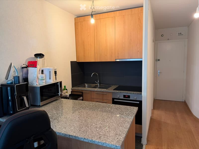 Modern kitchen with granite countertop, wooden cabinets, microwave, coffee maker, oven, sink, and various appliances.