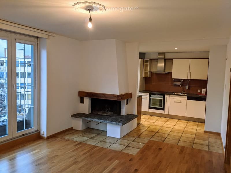 Furnished Room. Open-plan living and dining area with a fireplace, wooden flooring, and a modern kitchen with white cabinets, an oven, and a sink.