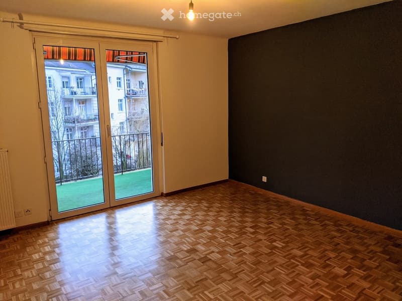Unfurnished Room. Empty room with wooden parquet flooring, large sliding glass doors leading to a balcony, and a dark accent wall.