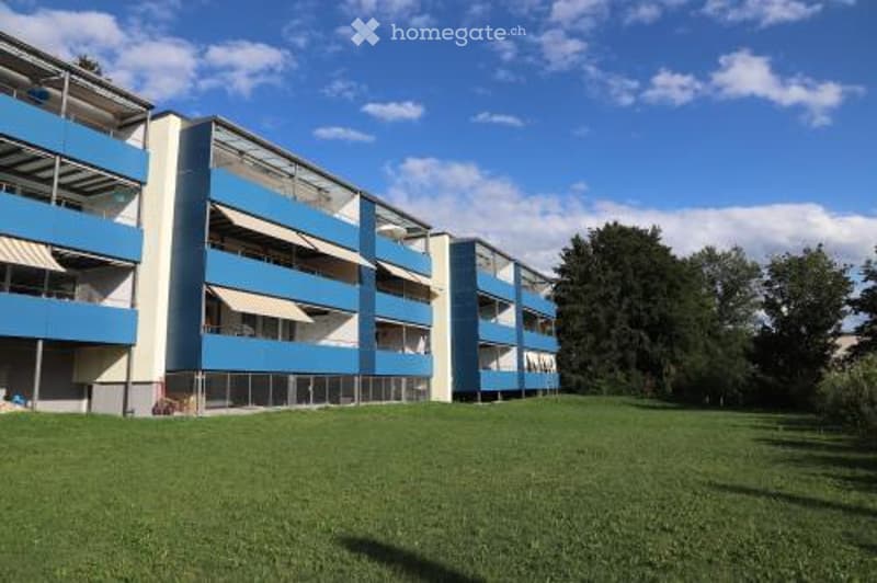 3 story apartment complex, blue and white, balconies on each floor, large grassy area