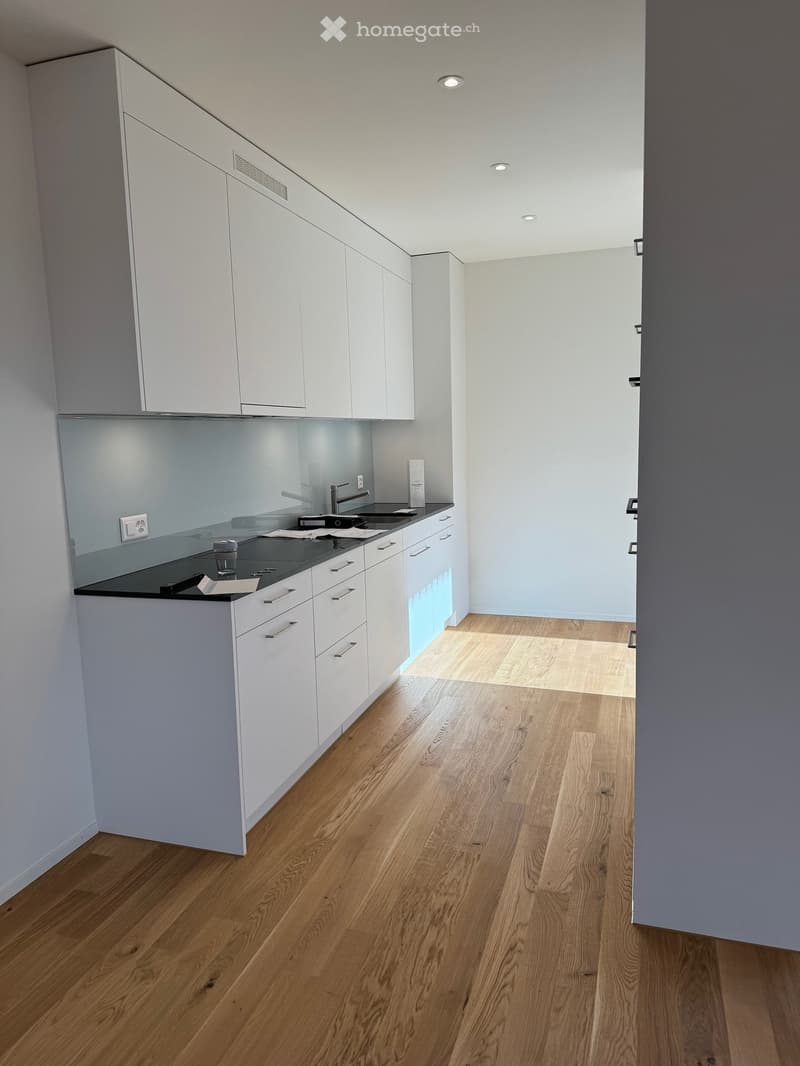 modern kitchen with white cabinets, black countertops, glass backsplash, stainless steel sink, faucet, and electrical outlets