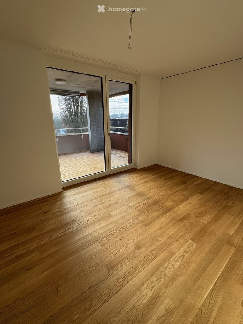 empty room, wooden floor, sliding glass doors, balcony, view of trees and buildings