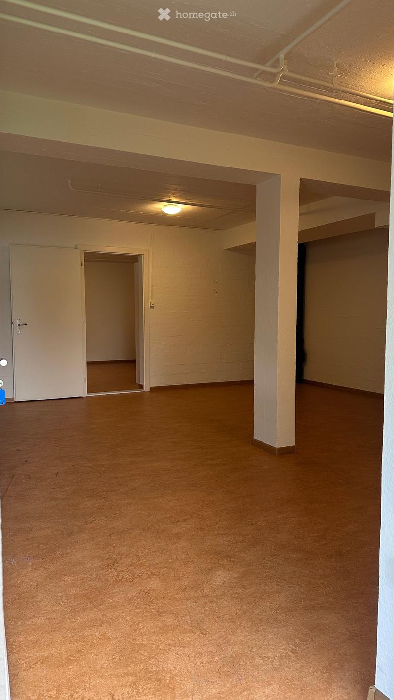 Empty room with wooden flooring, white walls, and a single door leading to another space.