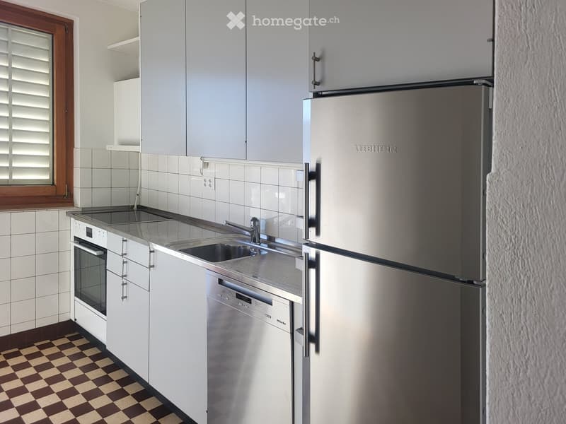 Modern kitchen with white cabinets, stainless steel appliances, and a checkered floor.
