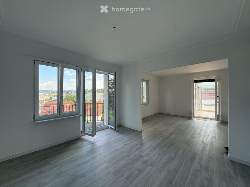 Empty room with wooden flooring, large windows, and open doors leading to a balcony and another room.