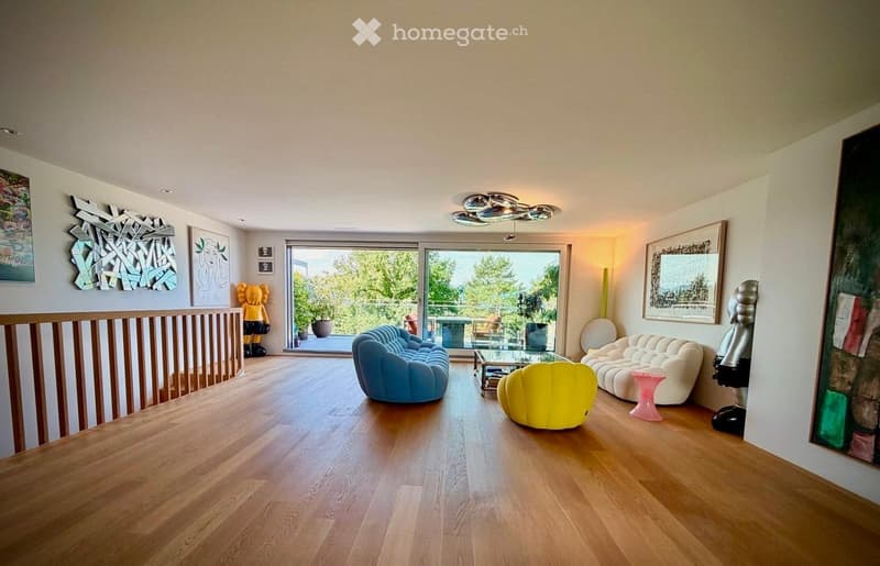 Modern living room with light wooden flooring, large windows, and contemporary furniture including a blue sofa, yellow chair, white sofa, glass coffee table, pink stool, and various art pieces.