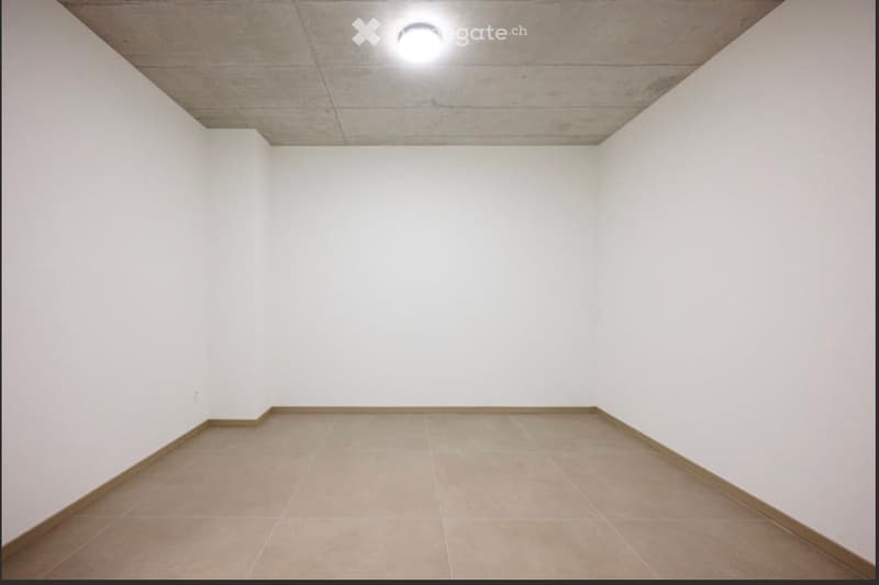 Empty room with white walls, tiled floor, and a single ceiling light fixture.