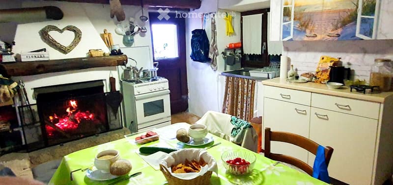 Cozy kitchen with a lit fireplace, stove, oven, dining table with cups and snacks, and cabinets.