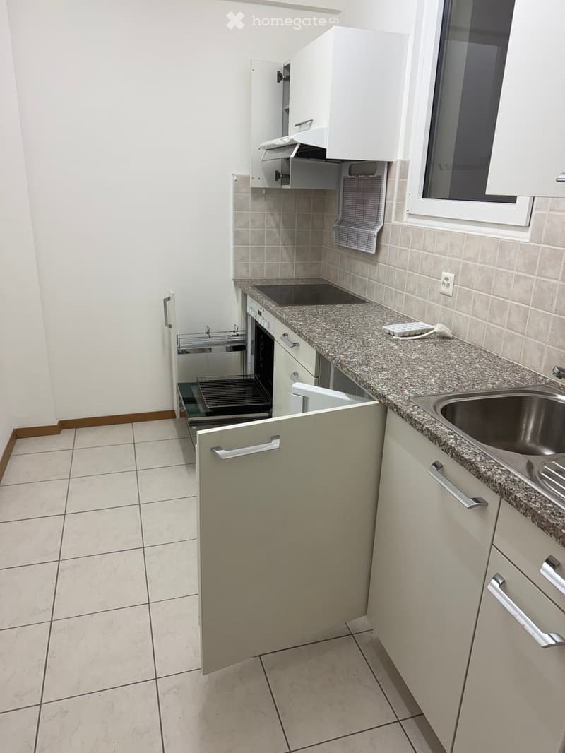 Modern kitchen with white cabinets, granite countertop, stainless steel sink, and built-in oven and dishwasher.