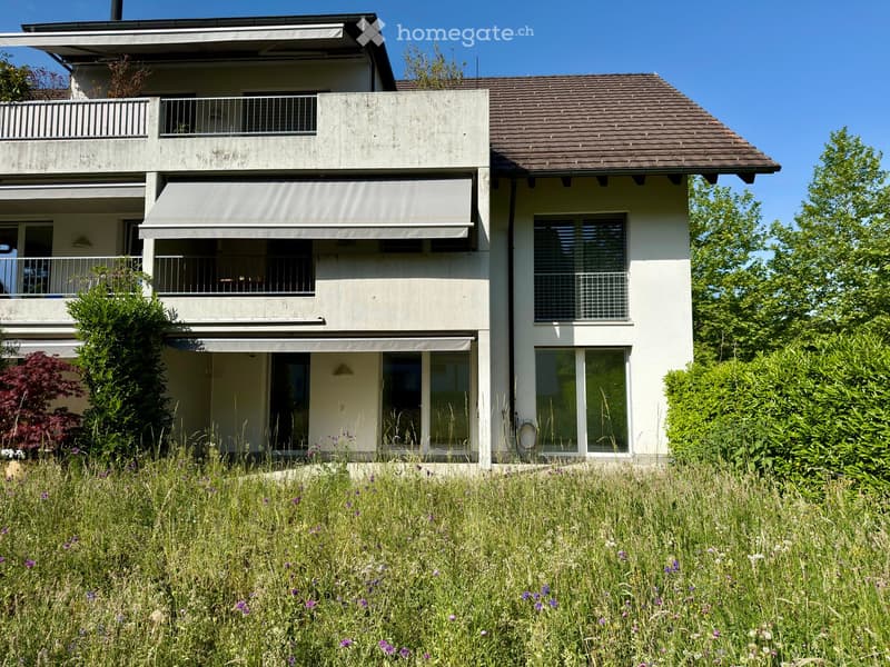 Two-story house with balconies, large windows, and a well-maintained garden.