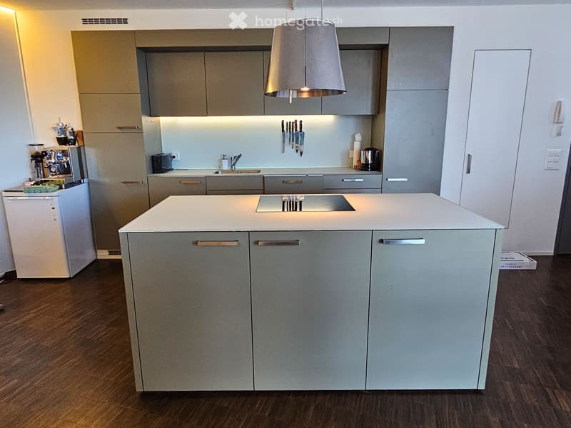 Kitchen. Modern kitchen with grey cabinets, white island, pendant light, coffee machine, and various appliances.