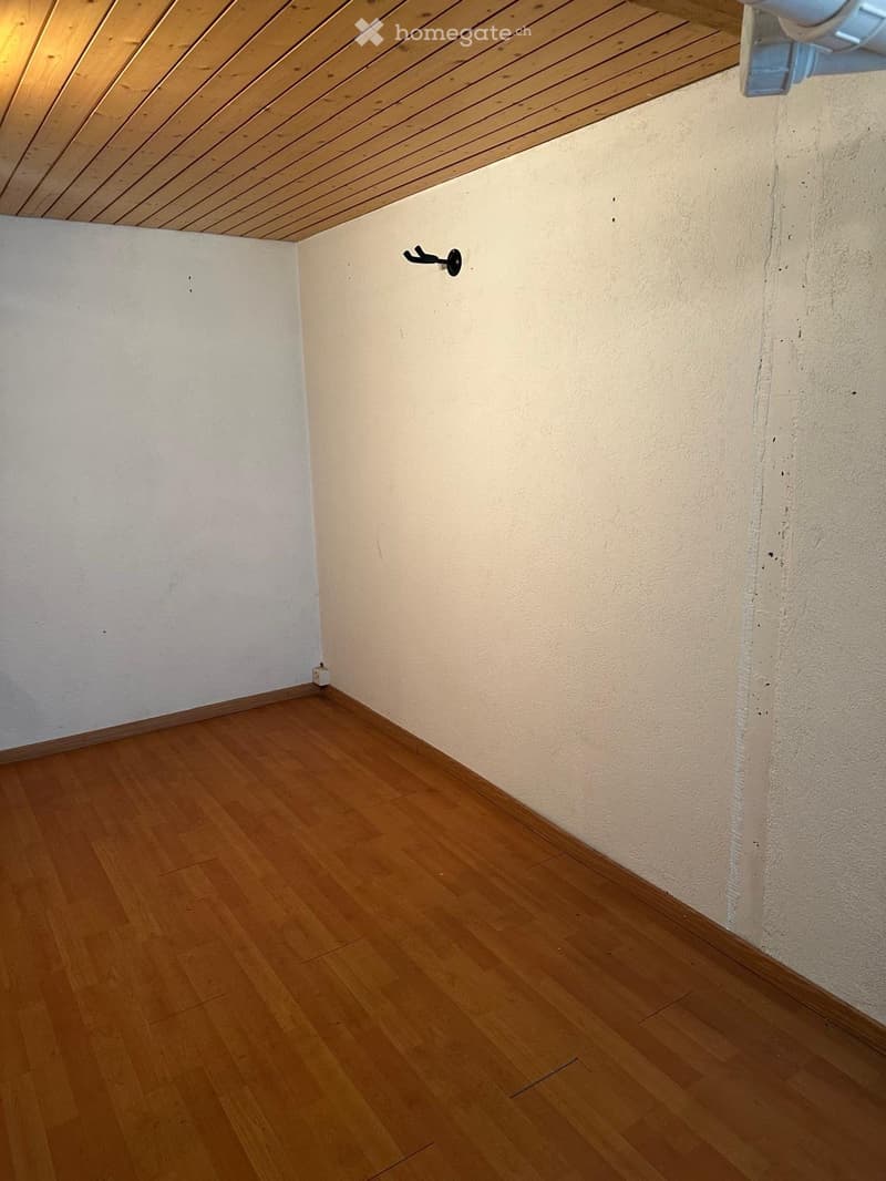 Empty room with wooden flooring, white walls, and a wooden ceiling. No furniture or equipment is present.