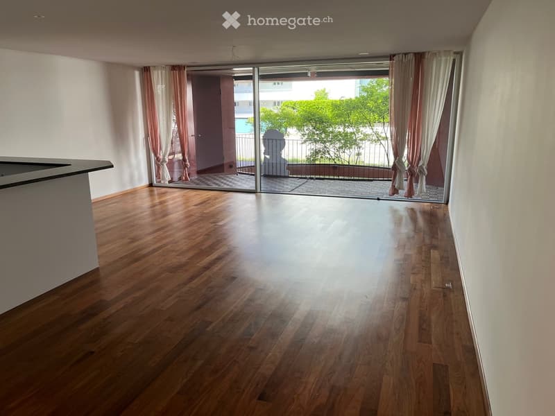 Empty room with wooden flooring, large sliding glass doors leading to a balcony, and light-colored walls.