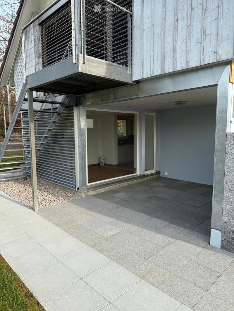 modern building, gray exterior, balcony, stairs, large glass door, paved exterior