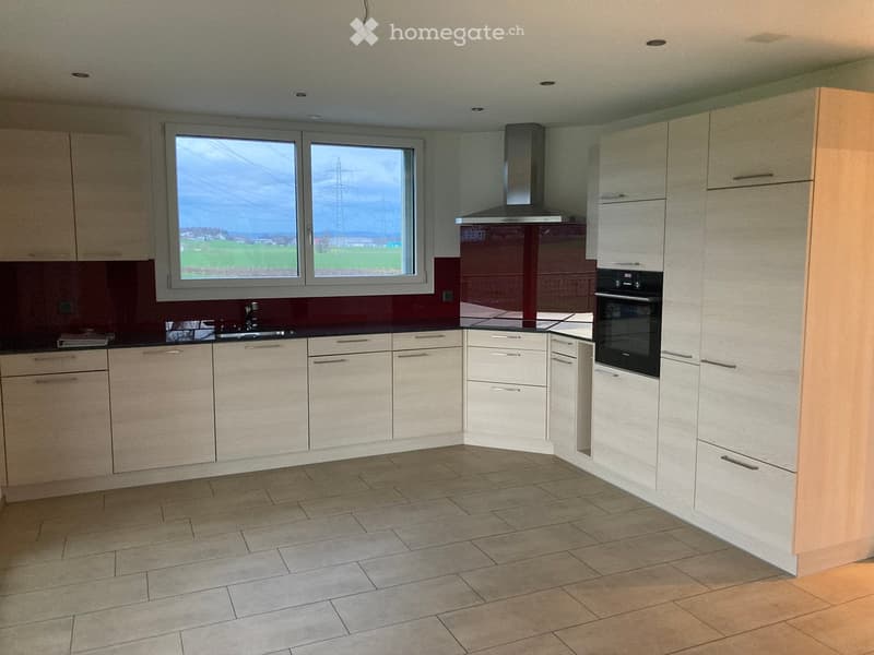 Modern kitchen with white cabinets, stainless steel appliances, and a large window overlooking a field.