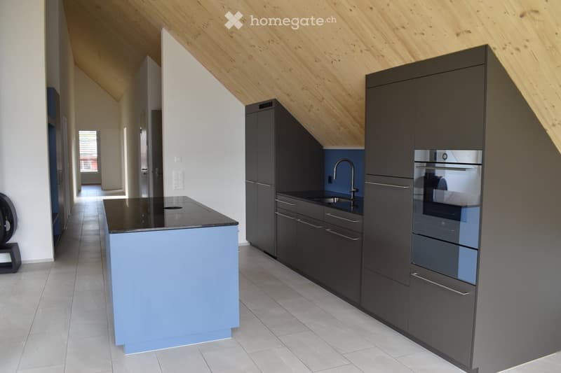 Modern kitchen with dark grey cabinets, light blue lower cabinets, black countertop, stainless steel sink, and built-in oven.