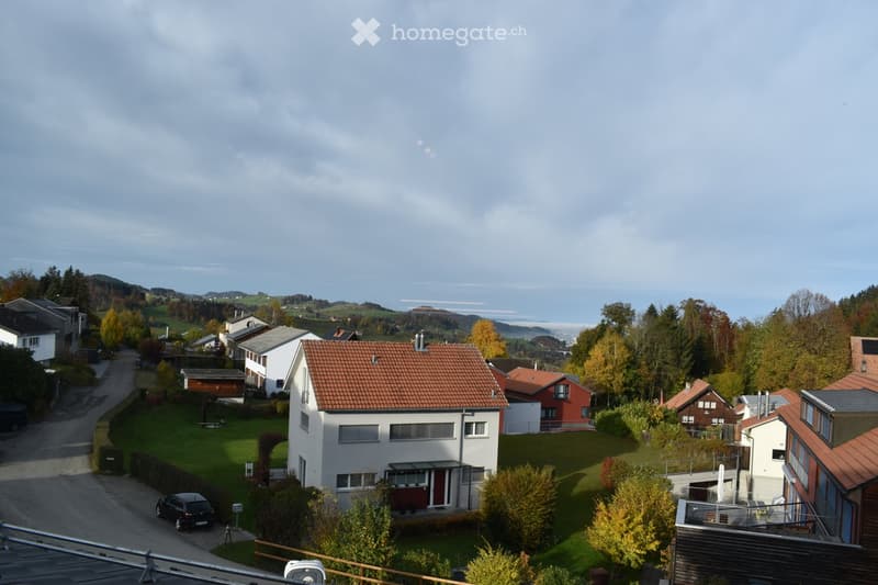 Aerial view of a residential neighborhood with multiple houses, red-tiled roofs, and surrounding greenery.