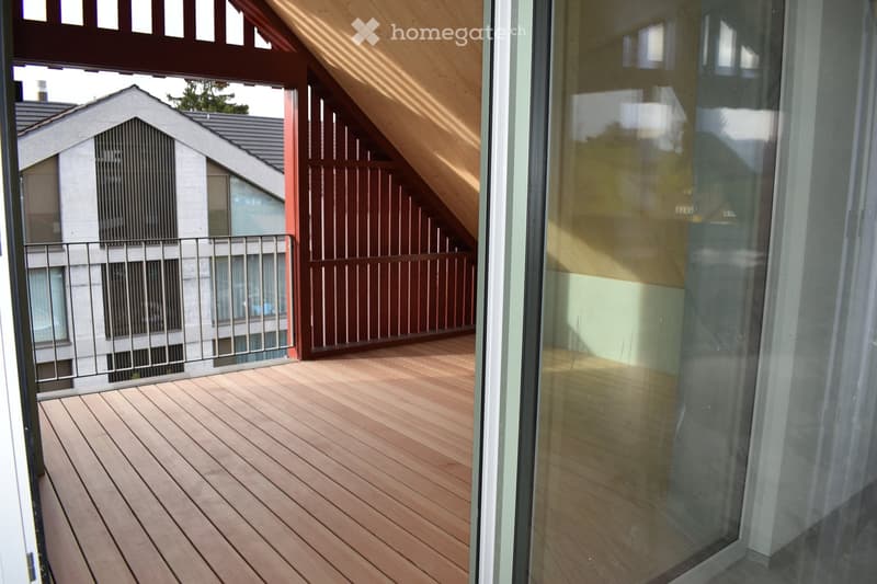 Wooden deck with metal railing, glass sliding door, and view of neighboring house.