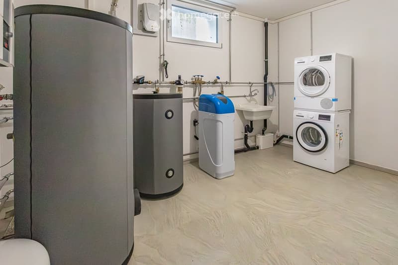 Modern utility room with a washing machine, water heater, water softener, and a small sink.