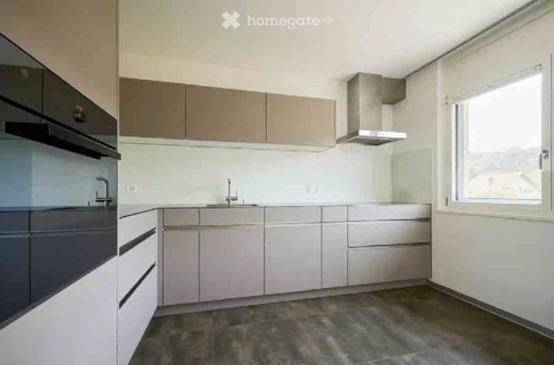 Modern kitchen with light-colored cabinets, stainless steel appliances, and a large window providing natural light.