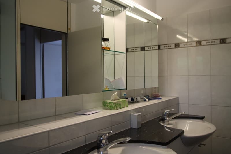 Modern bathroom with two sinks, mirrored cabinets, and a black countertop.