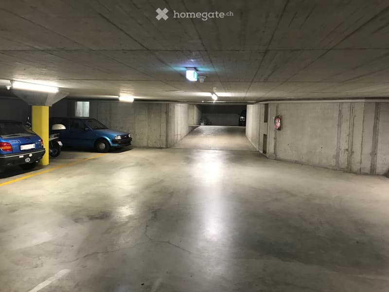 underground parking, yellow and white markings, concrete walls, fire extinguisher, cars parked