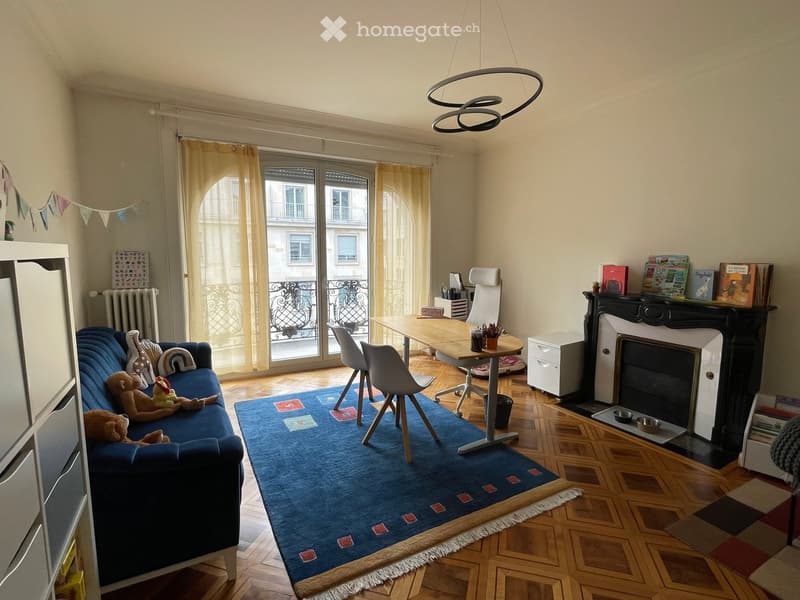 Living room with a blue sofa, wooden table, chairs, fireplace, and a balcony view.