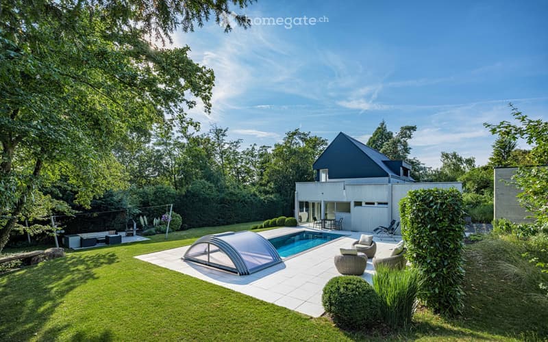 Modern garden with a swimming pool, lounge chairs, a barbecue, and a contemporary house in the background.