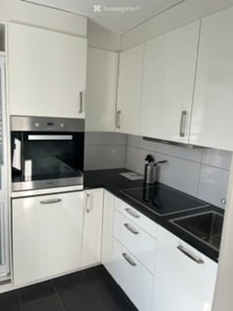 Modern kitchen with white cabinets, black countertops, and stainless steel appliances.