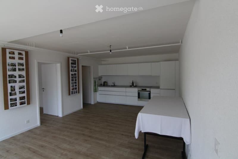 wooden floor, white walls, kitchen island, white cupboards, table, mounted lamps
