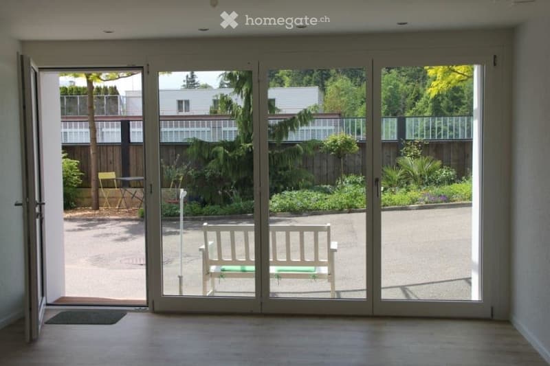 Open sliding doors, green bench, carpeted entry, view of outside garden and trees