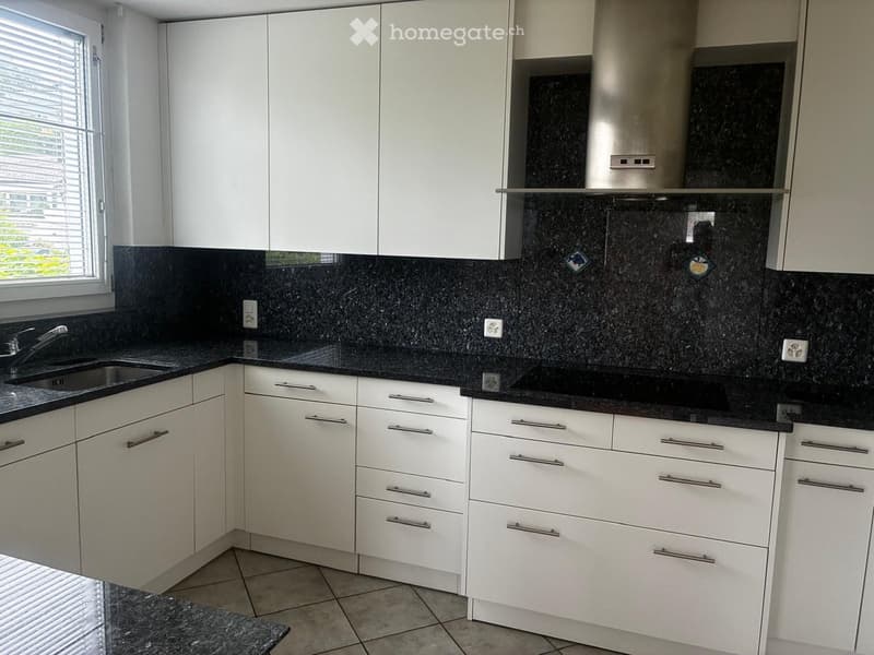 Modern kitchen with white cabinets, black granite countertops, a stainless steel range hood, and a sink with a faucet.