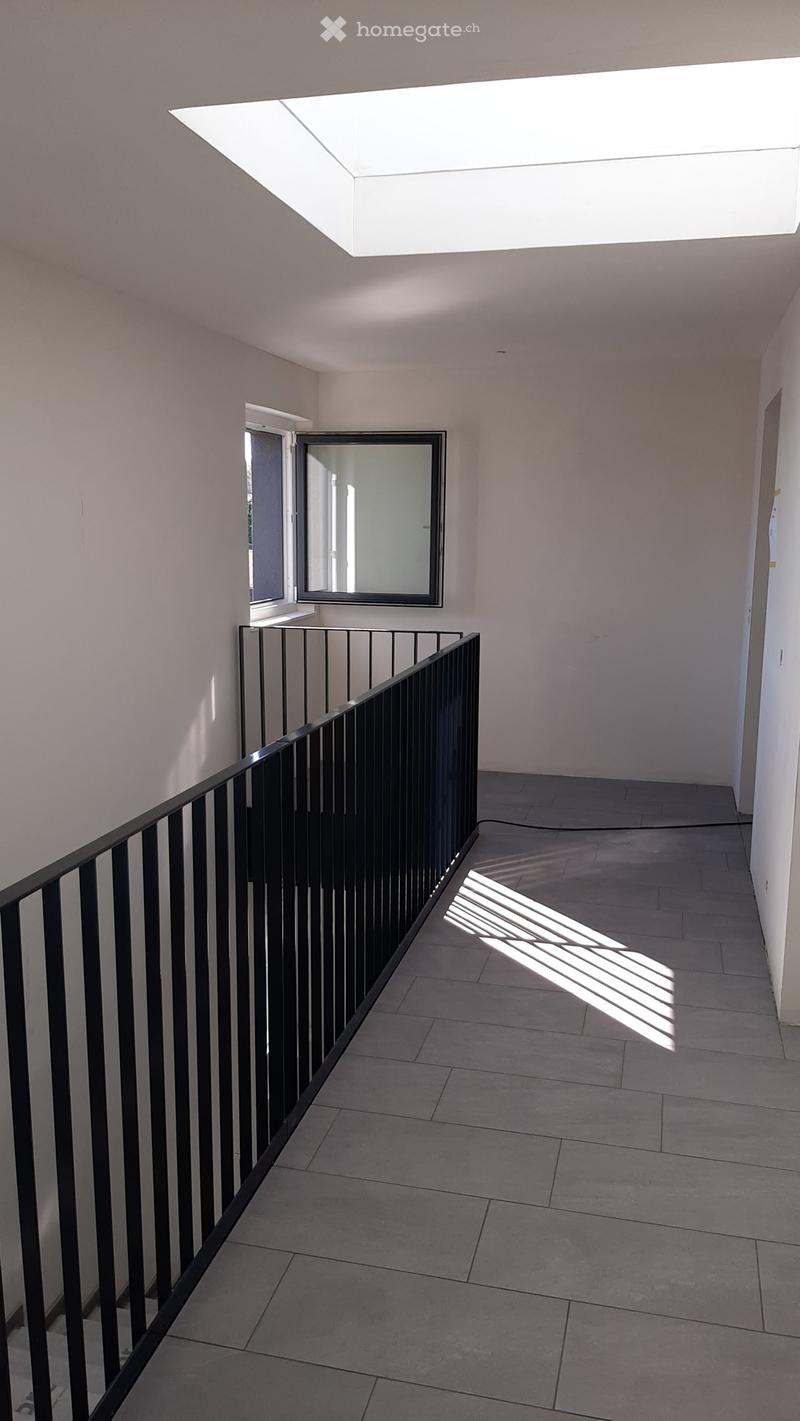 Balcony with black railing, white ceiling, window, tiled floor, light shadows on floor