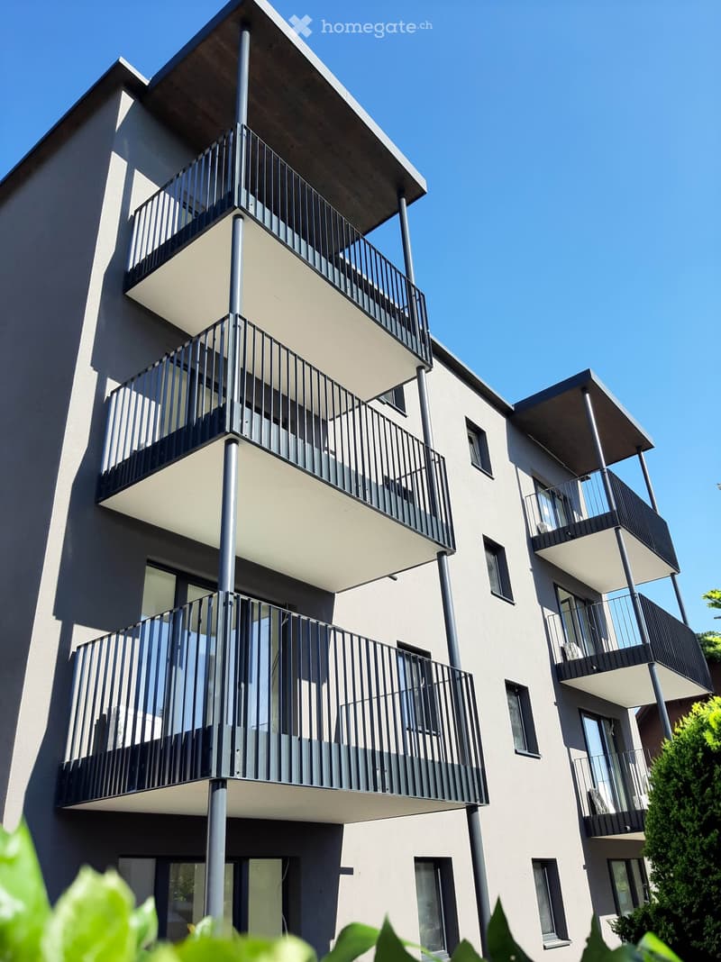 Multi-story apartment building, balconies on each floor, gray exterior, white accents, modern design