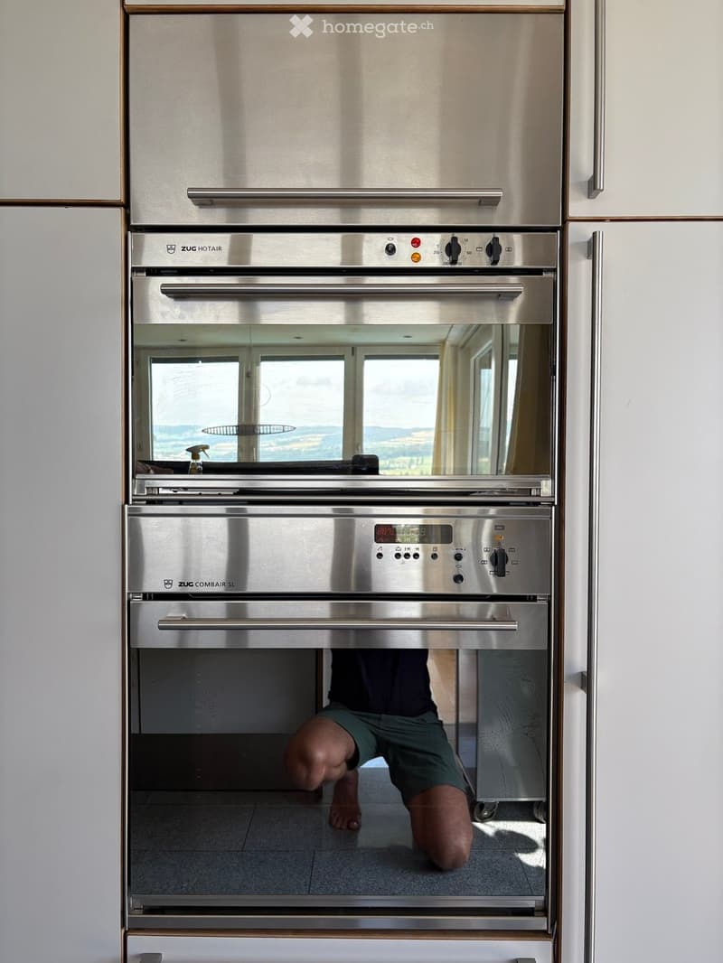 large modern oven with digital display, stainless steel finish, view through glass door to exterior