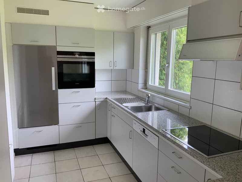 Modern kitchen with white cabinets, stainless steel appliances, granite countertop, and large windows.