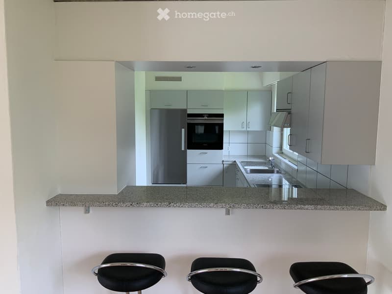 Modern kitchen with white cabinets, granite countertop, stainless steel appliances, and three black bar stools.