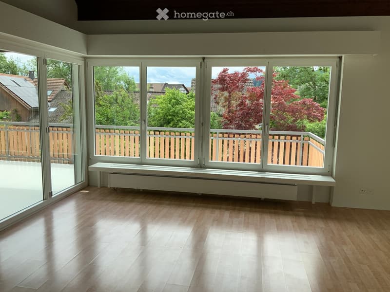 Empty room with wooden flooring, large windows, and a radiator under the windows.