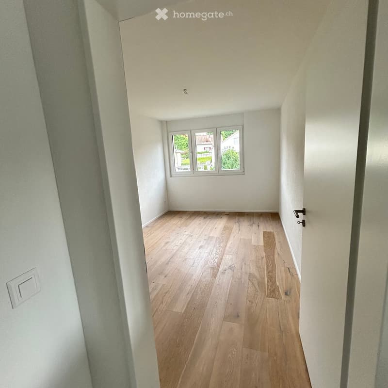 Empty room with wooden flooring, white walls, and a window showing a view of the outside. No furniture or equipment is present.