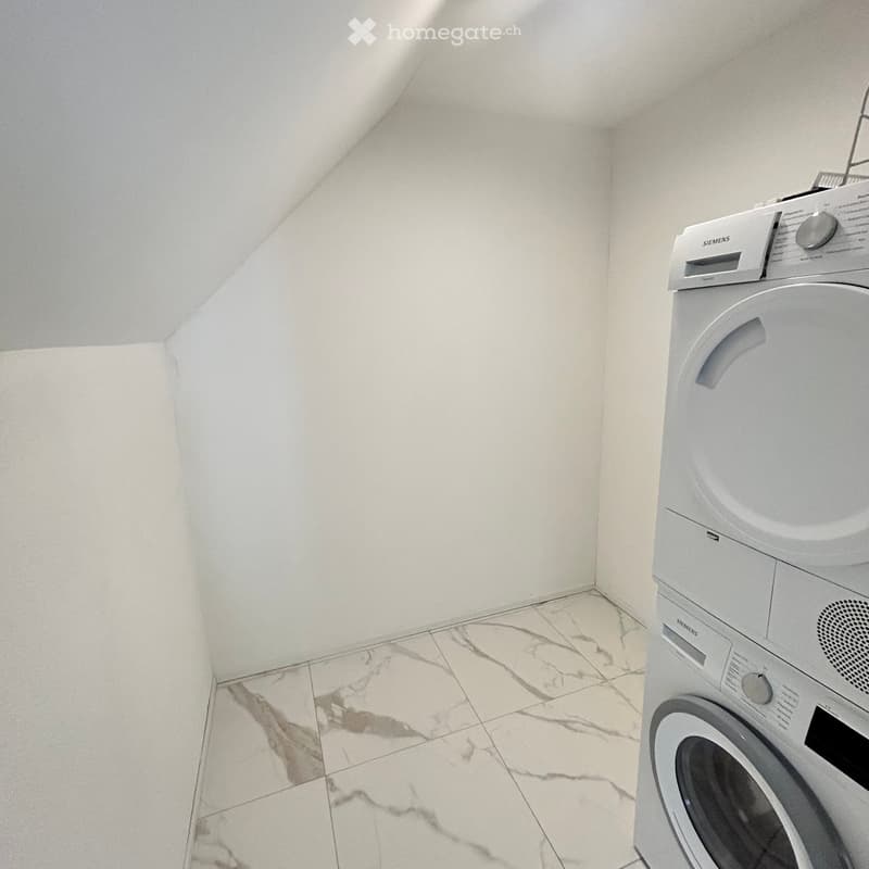 A small, clean room with a white washing machine, marble tiled floor, and white walls.