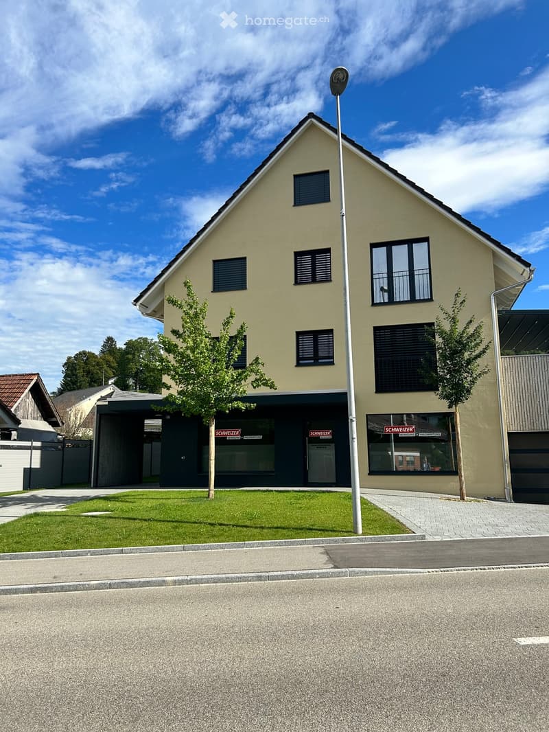 Two story house, beige wall, two garage doors, trees on front, sign on windows