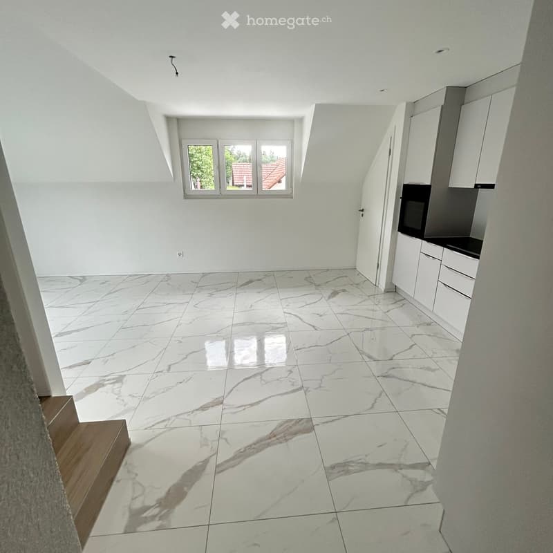 Empty room with white walls, marble flooring, and built-in cabinets. Natural light from a window at the far end.