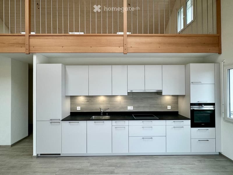modern kitchen with white cabinets, black countertops, stainless steel sink, gas stove, oven, wooden balcony