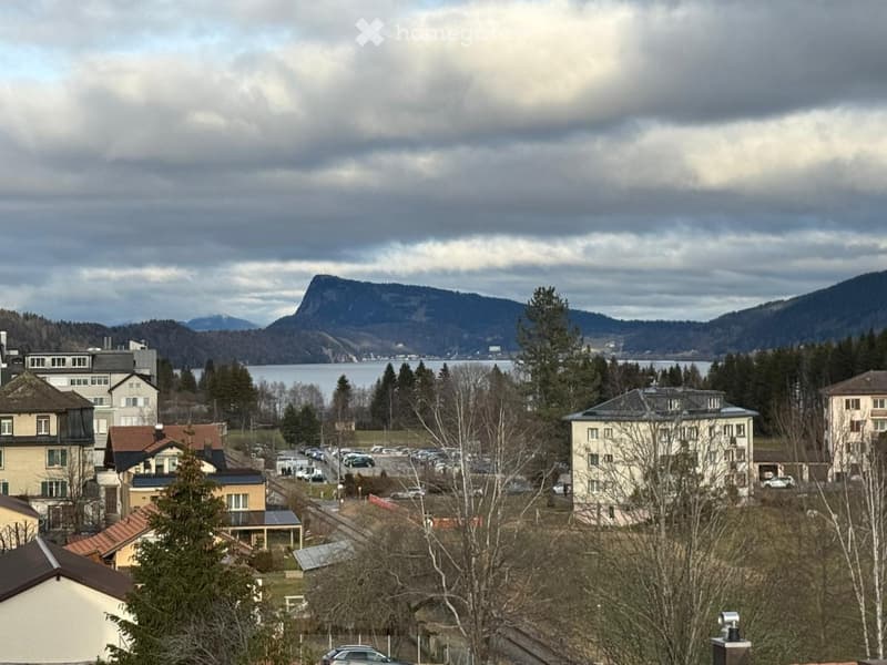 Aerial view of a town with buildings, a lake, and mountains in the background