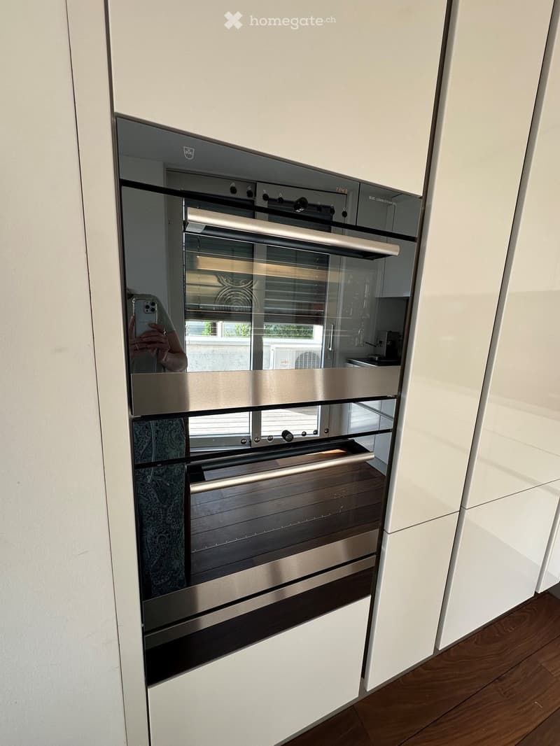 Modern kitchen with a built-in stainless steel oven featuring multiple compartments and control knobs.