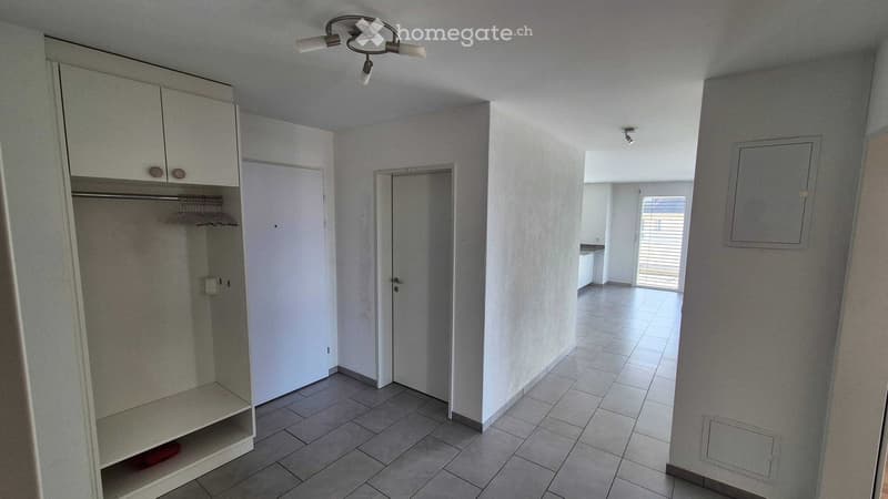 Empty hallway with tiled floor, white walls, built-in closet with shelves, and a door leading to another room.