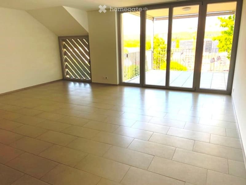 Empty room with wooden flooring, large sliding glass doors leading to a balcony, and a small decorative screen on the left side.