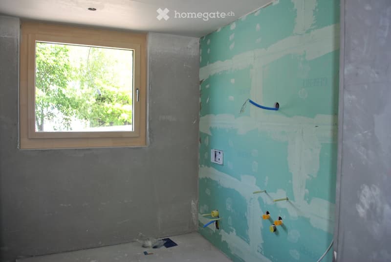Empty room with unfinished walls, a window, and exposed electrical wiring and outlets. No furniture or furnishings present.