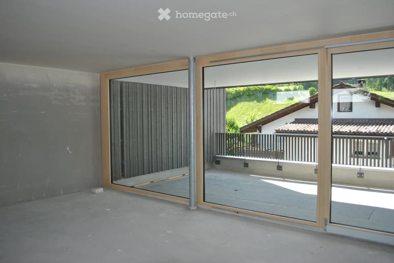 Empty room with large glass sliding doors leading to a balcony, concrete floor, and grey walls.