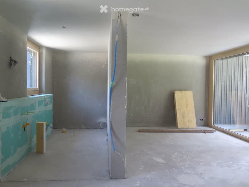 Empty room with unfinished walls and floor, featuring a concrete pillar, a window, and a partially painted wall. No furniture or equipment present.